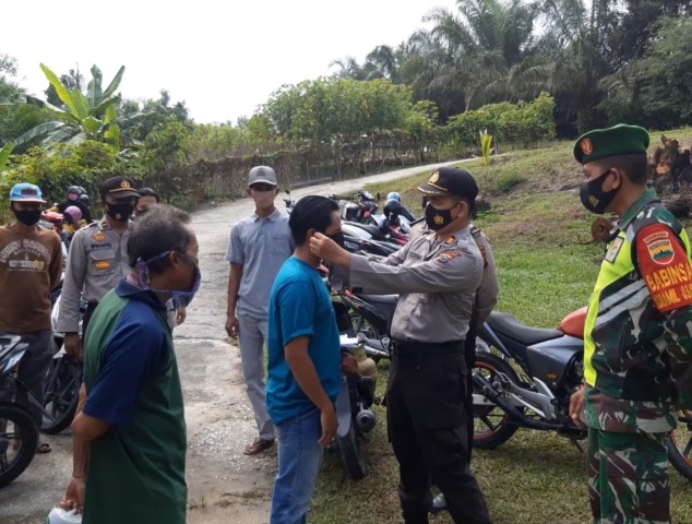 Cegah Penularan Covid19, Kapolsek Kerinci Kanan Pasangkan Masker ke Warga