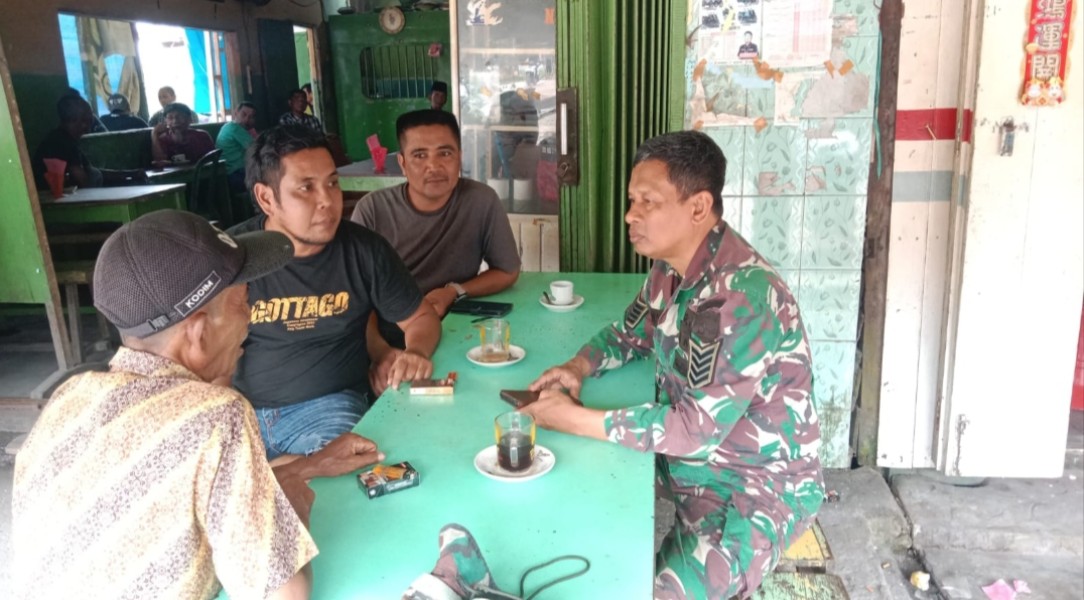 Santai di Warkop, Babinsa Koramil 05/Gas Serma Nawawi melaksanakan Komsos Bersama Masyarakat