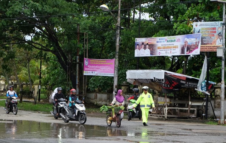 Tak Perduli Hujan Gerimis, Anggota Lantas Polres Inhil ini Tetap Melakukan Pengaturan Lalu Lintas