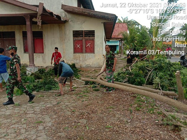 Anggota Koramil 03/Tempuling Bantu Warga Bersihkan Halaman Gedung Serba Guna